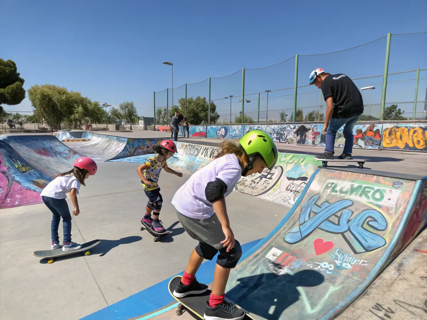 A modern skatepark with ramps, rails, and bowls, filled with skaters of all ages enjoying the facilities.