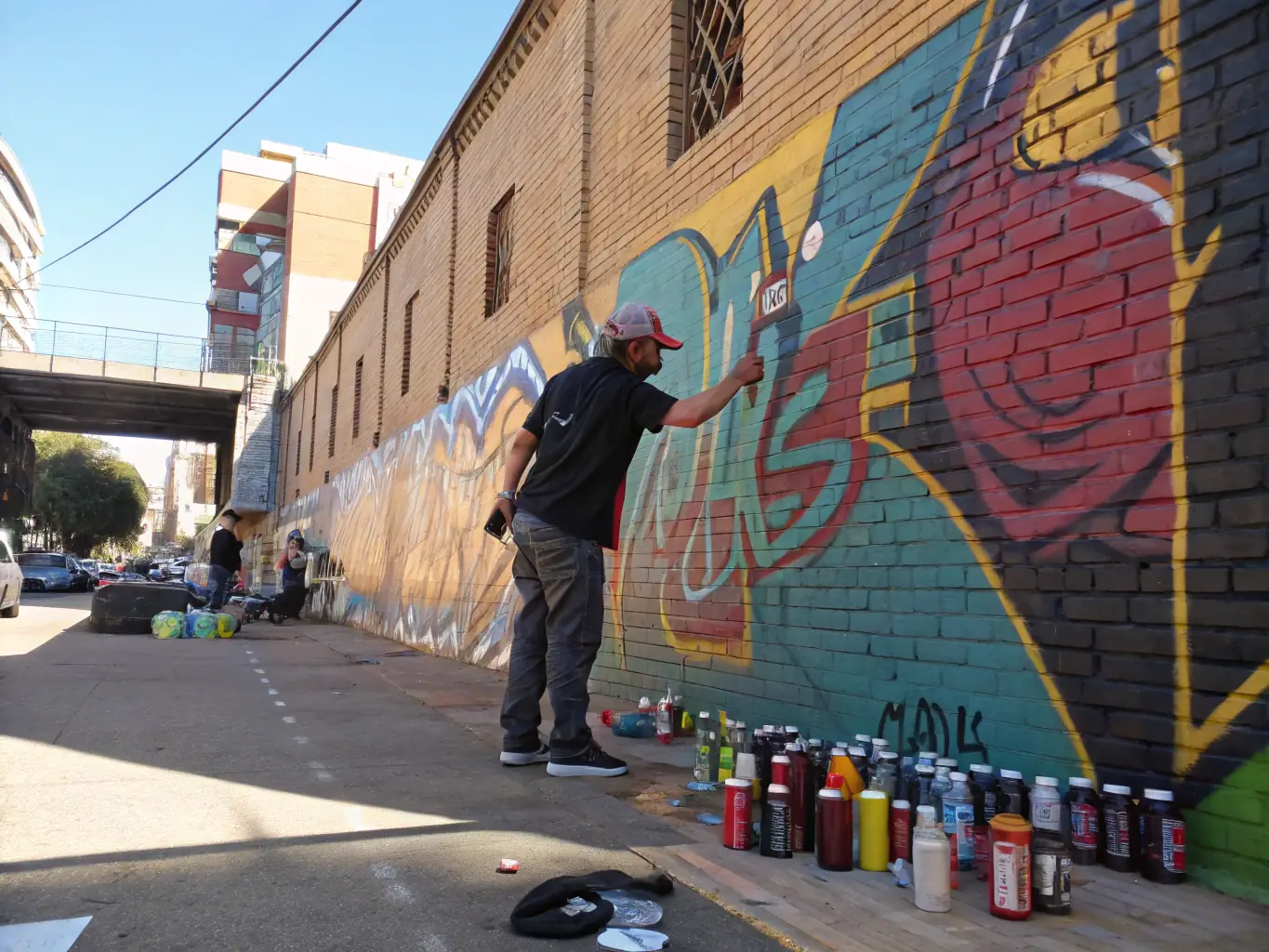 A group of young people participating in an urban arts workshop, learning graffiti techniques from a professional artist.